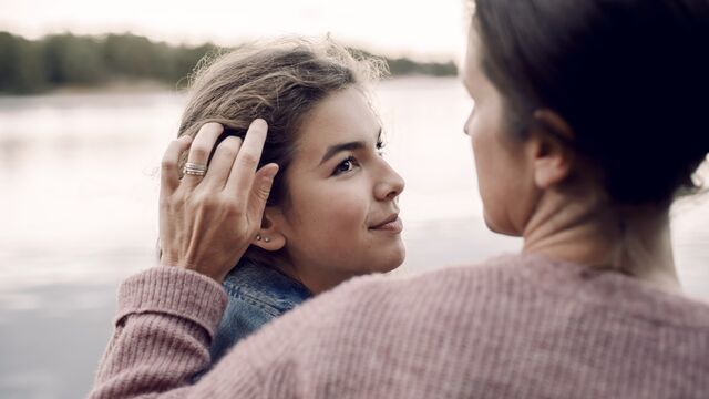 Smiling daughter looking at caring mother by lake - small
